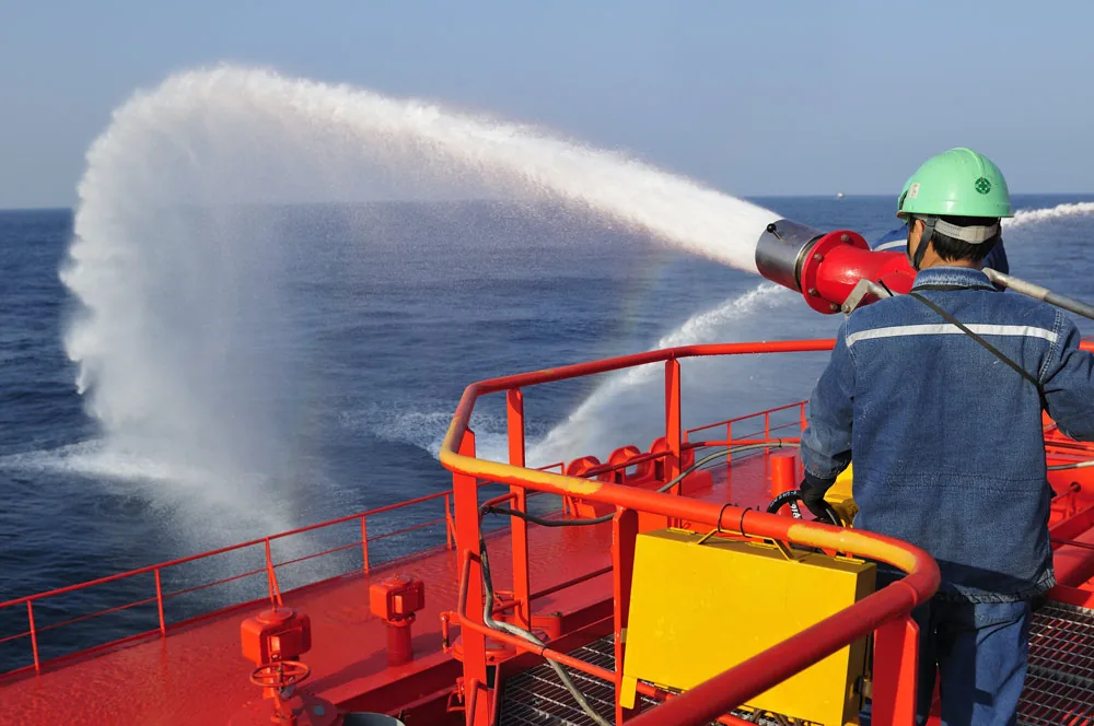 Crew member operating a fire-fighting monitor on a ship's deck